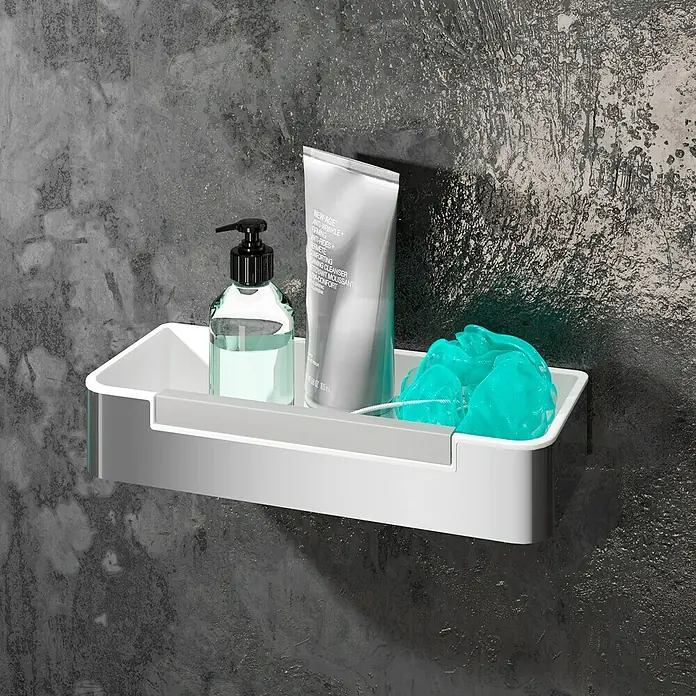 Cesta de baño Concept - 12 x 29 x 5,3 cm, Plástico, Blanco - Primer plano de una estantería blanca con una botella, un tubo y una esponja de baño azul sobre una pared oscura.