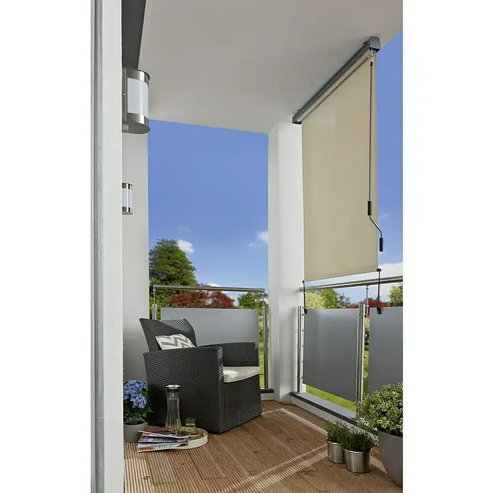 Sunfun Balkonverschattung - Beige, Breite: 1,4 m, Ausfall: 2,5 m - Balkon mit einem cremefarbenen Rollo, das teilweise heruntergelassen ist, neben einem Rattansessel mit Kissen und Beistelltisch.