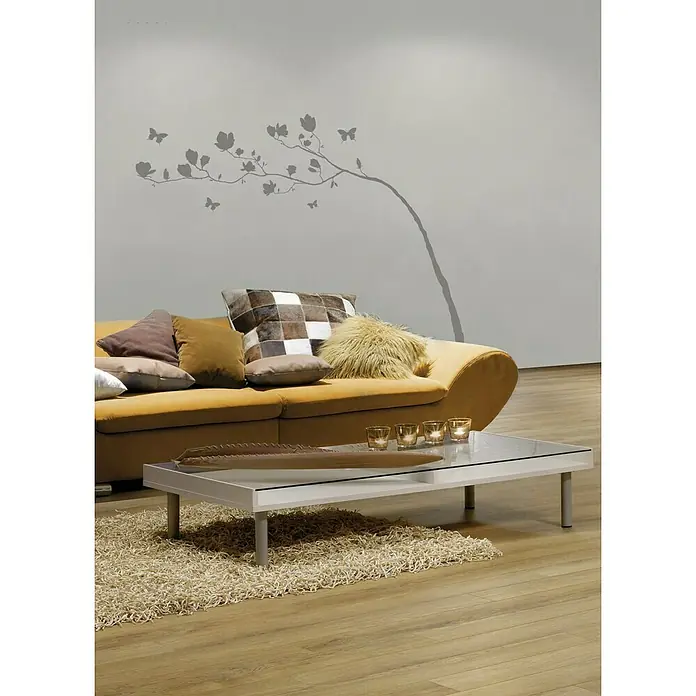 Komar Dekosticker Arabesque - Silber, 70 x 100 cm - Wohnzimmer mit gelbem Sofa, Couchtisch aus Glas und Wandaufkleber.