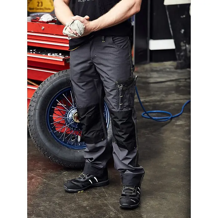 Terrax Workwear Herren-Arbeitshose - 56, Grau, Gelb - Das Bild zeigt eine robuste Arbeitshose mit verstärkten Knien und praktischen Taschen, ideal für Handwerker.