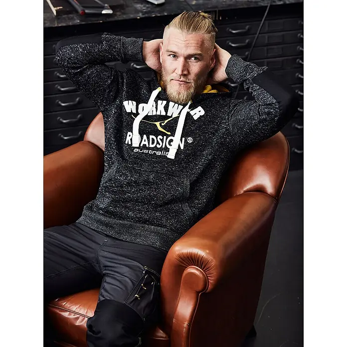 Terrax Workwear Kapuzenpullover - L, Grau - Der Mann trägt einen Roadsign Australia Hoodie und sitzt lässig in einem Ledersessel. Bequeme und stilvolle Arbeitskleidung für den Alltag.