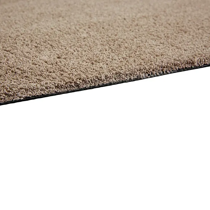 Fußmatte Moon - Taupe, 100 x 60 cm, 100 % Polyester - Detailaufnahme eines beigen Teppichs. Die Textur und die Kante des Teppichs sind gut sichtbar.
