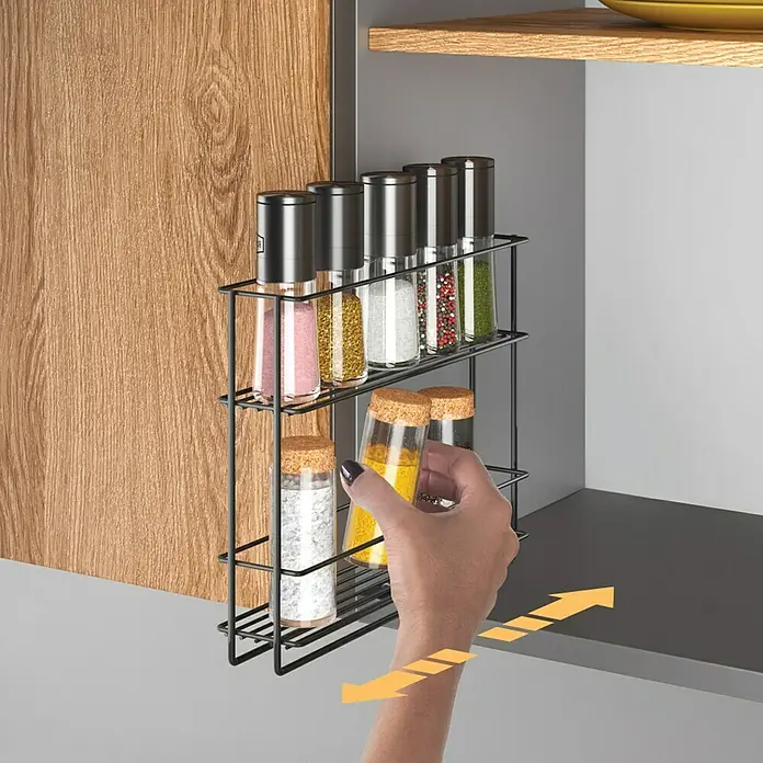 Metaltex Gewürzregal In&Out ausziehbar - L x B x H: 6 x 8 x 22 cm, Metall, Lavaschwarz - Schwarzes Metall-Auszugsregal für Gewürze im Schrank, mit Gläsern. Eine Hand zieht ein Gewürzglas heraus.