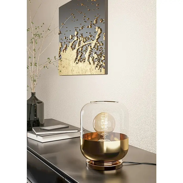 Eglo Maryvilla Tischleuchte - 40 W, Brüniert, E27 - Nahaufnahme einer modernen goldenen Tischlampe mit Glaskuppel, die auf einem schwarzen Tisch steht, mit Kunstwerk und Vase im Hintergrund.