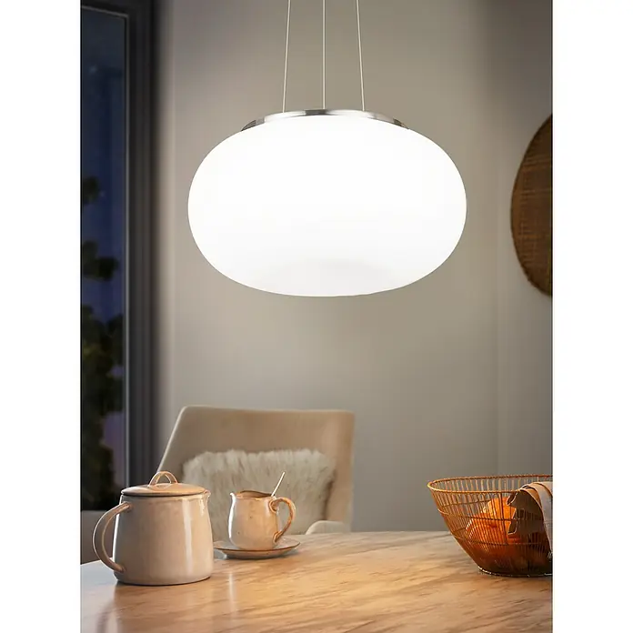 Eglo Pendelleuchte - 120 W, Ø x H: 445 mm x 110 cm, E27 - Das Foto zeigt eine moderne, runde Hängelampe mit silbernem Rand, die über einem Esstisch mit Geschirr und Obst hängt.