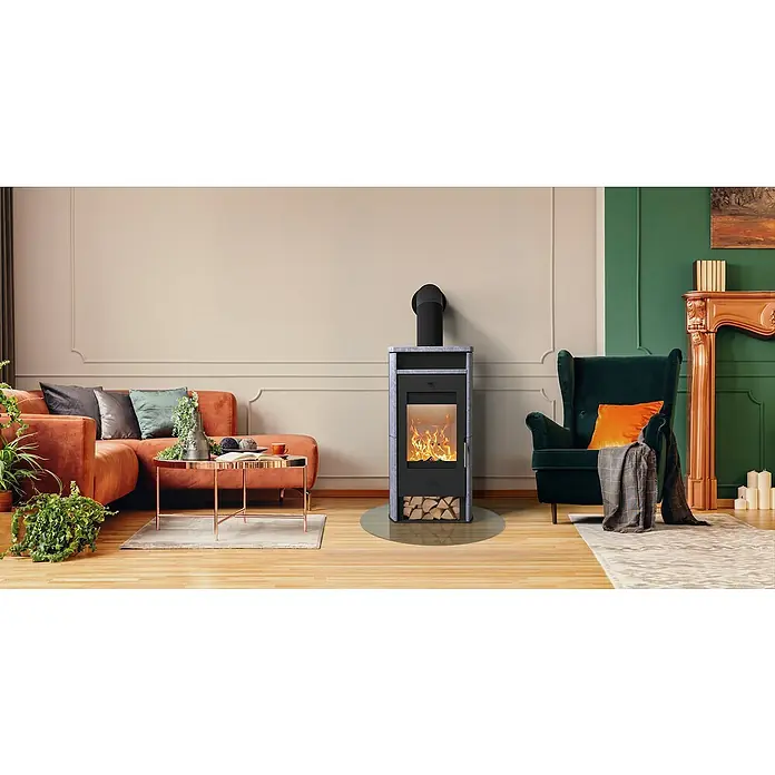 Kaminofen Santa Fe - 6 kW, Raumheizvermögen: 108 m³, Material Verkleidung: Speckstein, Schwarz - Schwarzer und grauer Kaminofen mit brennendem Feuer, Holzfach und Bodenschutzmatte in einem Wohnzimmer.