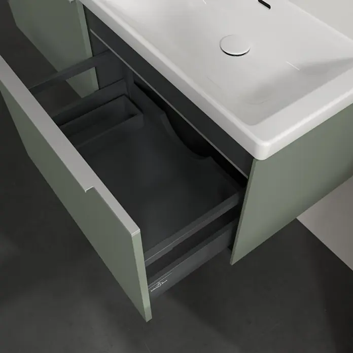 Villeroy & Boch Subway 3.0 Waschbeckenunterschrank - Soft Green, Anzahl Schubladen: 2 Stk., Farbe Griff: Aluminium glänzend, B x T x H: 127,2 x 47,8 x 42,9 cm, Mit Beleuchtung, Geeignet für Doppelwaschtisch - Salbeigrüner Waschtisch mit weißem Waschbecken, offene dunkelgraue Schublade zeigt Organizer und Siphonausschnitt.