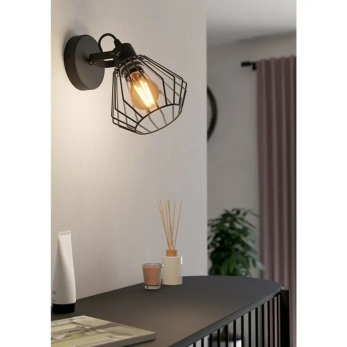Eglo Deckenstrahler TABILLANO - Schwarz, E27, 1 Stk. - Nahaufnahme einer stilvollen Wandleuchte mit einem schwarzen Metallkäfig, die ein warmes, einladendes Licht ausstrahlt.