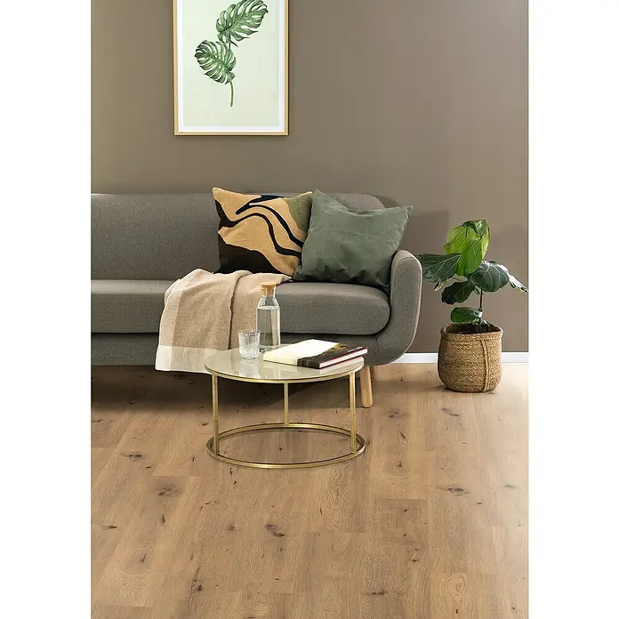 Egger Laminat NatureSense - Wildeiche Natur, Landhausdiele, 1.292 x 193 x 7 mm - Wohnzimmer-Szene mit modernem Sofa, Couchtisch mit goldenem Gestell und Zimmerpflanze. Das Bild zeigt eine harmonische und stilvolle Einrichtung.