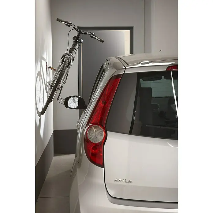Mottez Fahrrad-Wandhaken - Stahl, Rot - Silbernes Agila Auto in einer schmalen Garage geparkt, mit einem Fahrrad an der Wand.