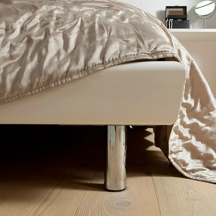 Element System Pata para muebles - Ø x Al: 6 x 20 cm, Capacidad de carga: 75 kg, Acero, Blanco - Vista detallada de una cama con colcha brillante y patas cromadas sobre un suelo de madera clara.