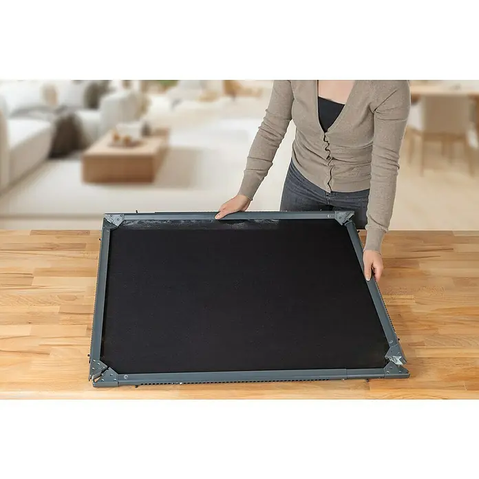 Easy Maxx Insektenschutzfenster - B x H: 115 x 135 cm, Montage Insektengitter: Klemmen, Farbe Rahmen: Anthrazit - Frau hantiert mit einer faltbaren Hundetreppe mit schwarzer Stoffoberfläche und grauem Rahmen auf einem Holztisch.