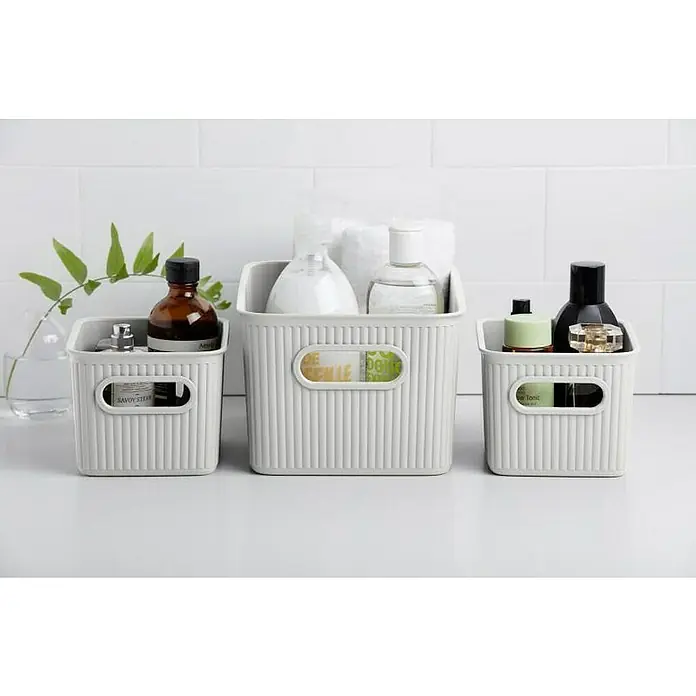 Tatay Baobab Cesta para la ropa - 18,1 x 27,2 x 13 cm, Plástico, Blanco - Tres cestos de almacenamiento blancos que exhiben diversos productos de baño, lo que demuestra una configuración de baño limpia y organizada.