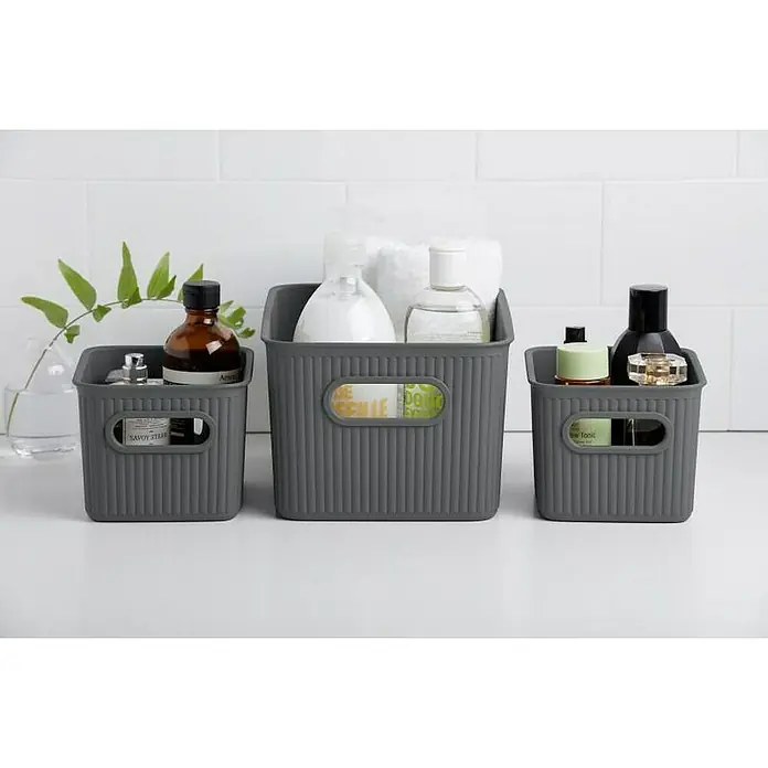 Tatay Baobab Cesta para la ropa - 18,1 x 27,2 x 13 cm, Plástico, Gris - Tres contenedores de almacenamiento grises con diversos artículos de baño sobre una superficie blanca, aportando orden y estilo al baño.