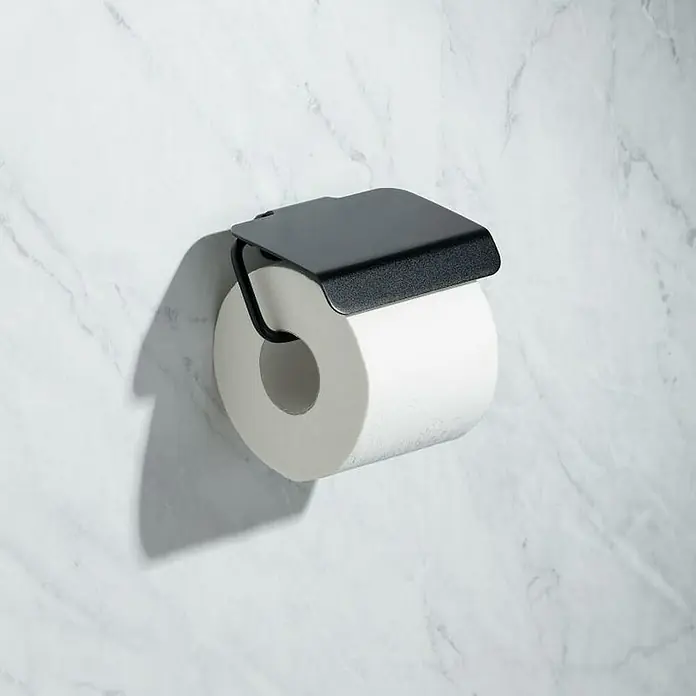 Tatay Onyx Portarrollos papel higiénico - Con tapa, Negro - Primer plano de un portarrollos de papel higiénico negro con un rollo de papel blanco en una pared de mármol.