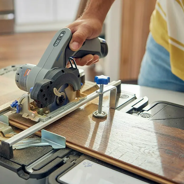 Dremel Akku-Handkreissäge Kompaktsäge Blueprint - 12 V, 1 Akku, 2 Ah, 5.000 U/min - Nahaufnahme einer Dremel Kreissäge beim Schneiden eines Holzstücks auf einer Werkbank, ideal für präzise Holzarbeiten.