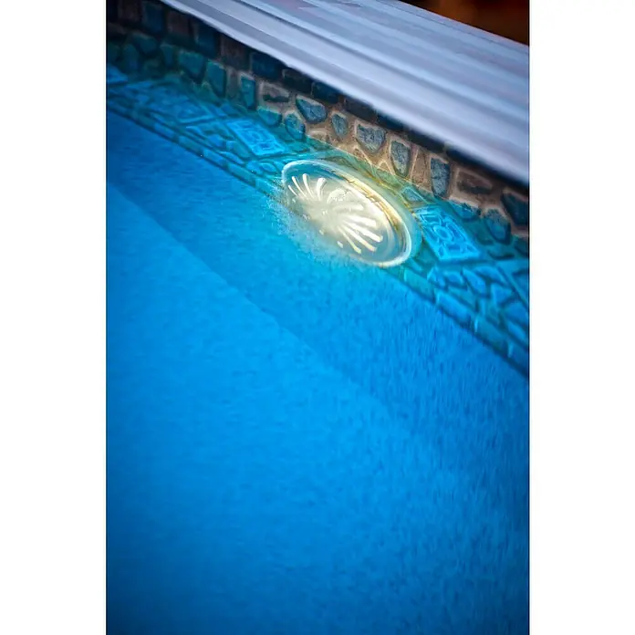 Gre Luz LED para piscinas Proyector - Blanco, LED - Primer plano de una luz de piscina bajo el agua, que proyecta un cálido resplandor en el agua azul, rodeada de azulejos y el borde de la piscina.