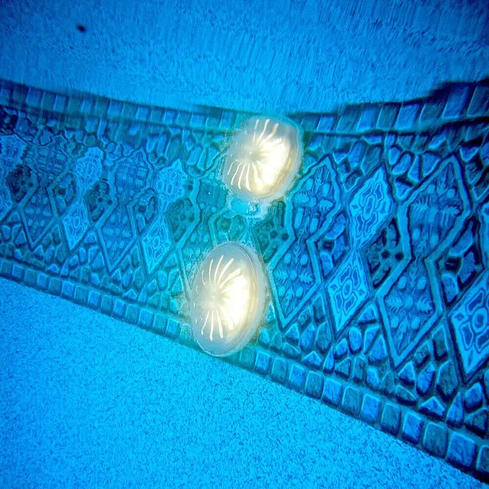 Gre Luz LED para piscinas Proyector - Blanco, LED - Primer plano de dos luces de piscina subacuáticas que realzan el vibrante patrón en el fondo de la piscina.