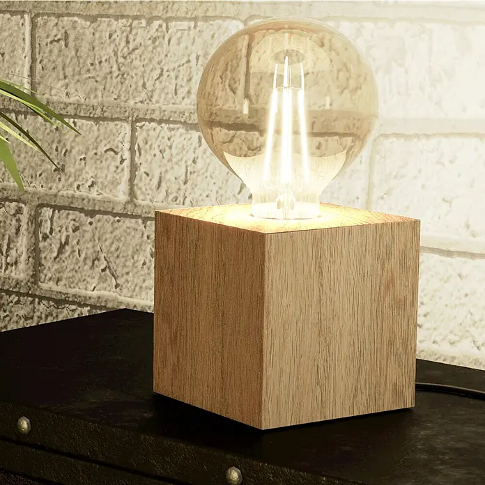 Eglo Tischleuchte PRESTWICK 2 - 40 W, L x B x H: 9,5 x 9,5 x 9,5 cm, Braun, E27 - Moderne Tischlampe mit quadratischem hellem Holzsockel und klarer kugelförmiger Edison-LED-Birne auf dunkler Oberfläche vor Ziegelwand.