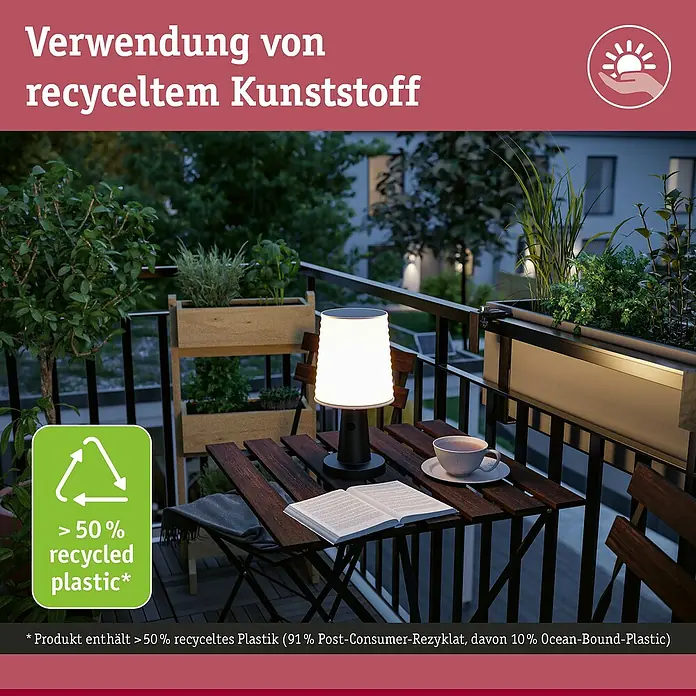 Paulmann Solar-Tischleuchte Ilanga - 32 W, Weiß/ Anthrazit, IP44 - Eine batteriebetriebene Tischleuchte aus recyceltem Kunststoff steht auf einem Balkontisch und beleuchtet ein Buch und eine Tasse.