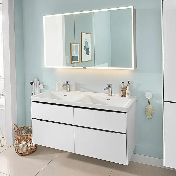 Villeroy & Boch Subway 3.0 Waschbeckenunterschrank - Brilliant White, Anzahl Schubladen: 4 Stk., Farbe Griff: Volcano Black, B x T x H: 127,2 x 47,8 x 57,6 cm, Mit Beleuchtung, Geeignet für Doppelwaschtisch - Weißer wandmontierter Doppelwaschtisch mit zwei Schubladen und schwarzen Griffen, darüber ein beleuchteter Spiegelschrank in einem modernen Bad.