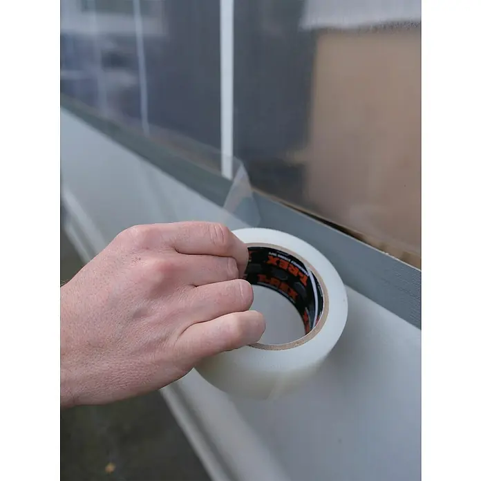 T-Rex Reparaturklebeband All Weather Tape - 25 m x 48 mm - Nahaufnahme einer Hand, die transparentes T-REX-Klebeband zum Abdichten eines Fensters verwendet.