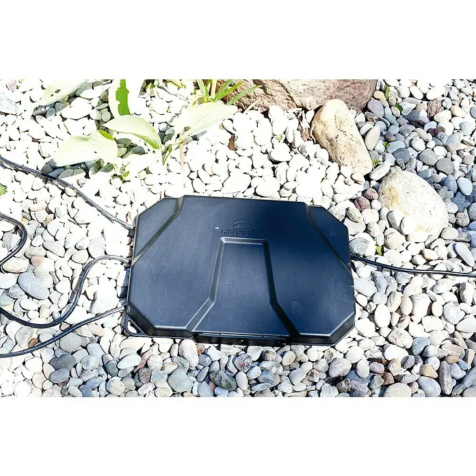 Heissner Garten-Aufbewahrungsbox - L x B x H: 40 x 30 x 21 cm, Kunststoff - Schwarzer, rechteckiger Heissner Outdoor-Stromverteiler mit Kabeln auf hellen Kieselsteinen.