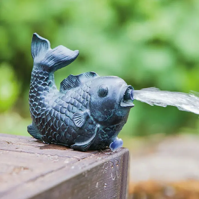 Heissner Wasserspeier Fisch - L x B x H: 77 x 152 x 125 mm - Fischförmiger Wasserspeier aus dunklem Metall, der Wasser aus dem Maul sprüht und auf einem nassen Holzsims ruht.