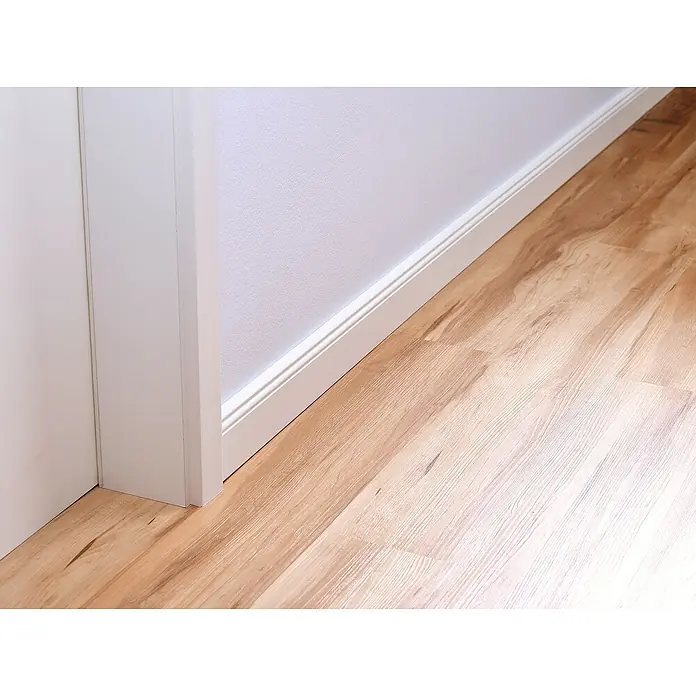 Tesa Powerbond Montageband für Tapete und Putz - L x B: 5 m x 19 mm - Detail eines Zimmers mit hellem Holzfußboden, weißen Fußleisten und einer weißen strukturierten Wand.