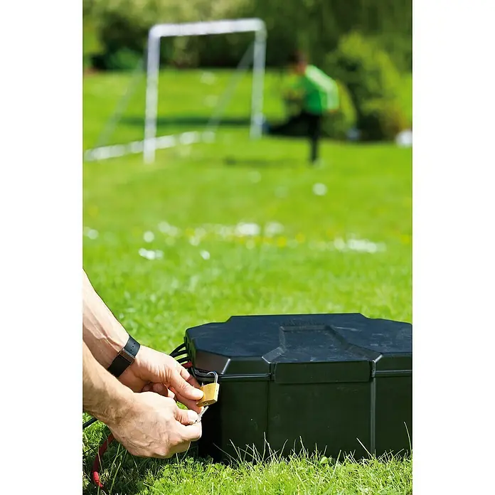 Heissner Garten-Aufbewahrungsbox - L x B x H: 40 x 30 x 21 cm, Kunststoff - Eine Person entriegelt eine schwarze Outdoor-Staubox mit einem Vorhängeschloss, im Hintergrund ein Kind und ein Fußballtor.