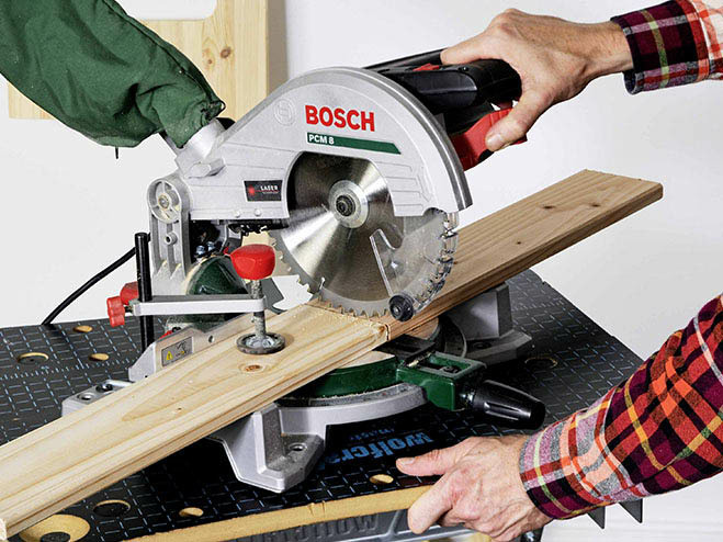 Mit einer Kappsäge wird ein Holzbrett zugeschnitten