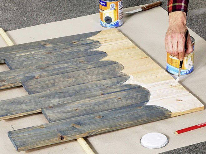 Auf Holzbrettern wird mit Buntlack ein Wellenmuster aufgemalt