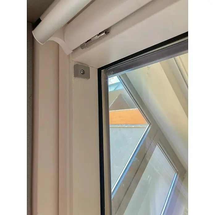 Velux Montage-Set ZOZ 230 - Passend für: VELUX Dachfenster & Sonnenschutzprodukte ab dem Baujahr 2000 - Nahaufnahme eines weißen Dachfensters mit Blick auf das Beschlagsdetail und das Glas mit Spiegelungen.