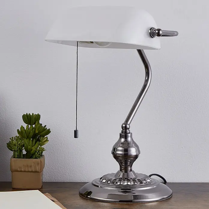 Eglo LED-Tischleuchte Banker - 60 W, L x B x H: 27,5 x 10 x 39 cm, Nickel-matt, Weiß - Bankerlampe aus poliertem Nickel mit weißem Glasschirm und Zugschnur, auf Holzschreibtisch neben Sukkulente und offenem Notizbuch.