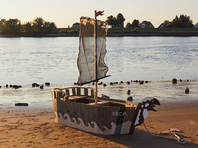 DIY Piratenschiff mit gehisster Flagge, am Wasser stehend
