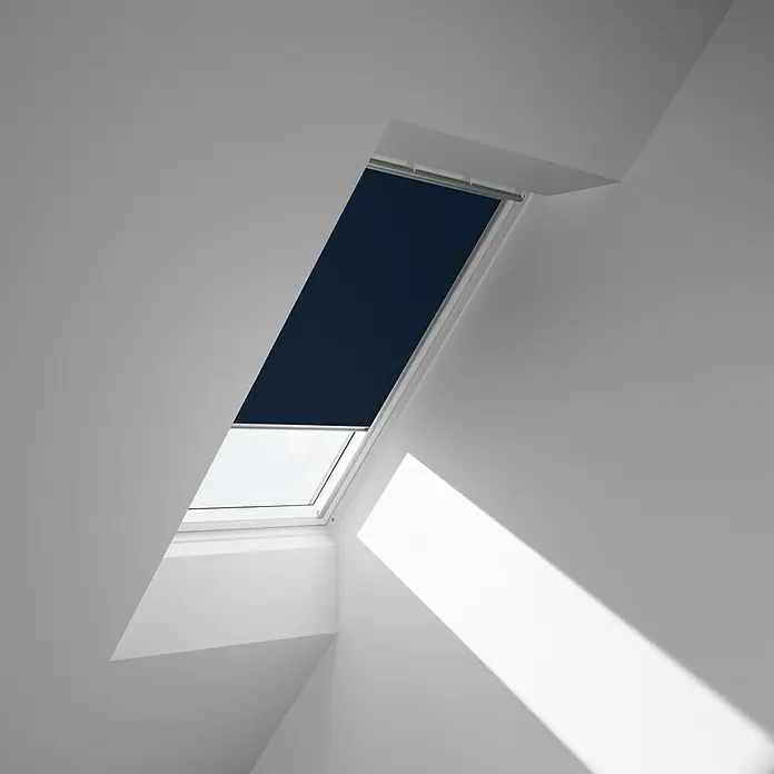 Velux Dachfensterrollo DKL FK06 1100S - Farbe: Dunkelblau - 1100S, Farbe Schiene: Aluminium, Manuell - Nahaufnahme eines Dachfensters mit Rollo in einem hellen Raum, das für Privatsphäre und Verdunkelung sorgt.