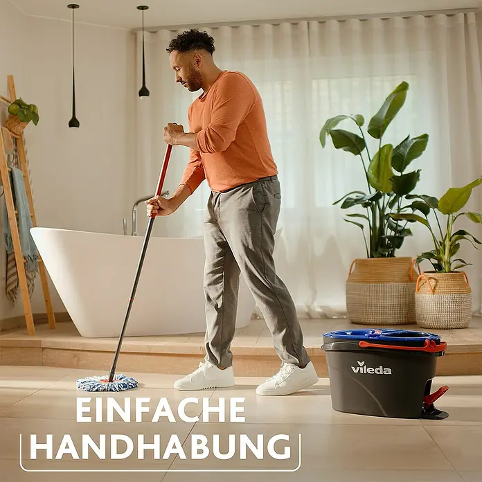 Vileda Bodenwisch-Set H2PRO Spin Mop System - 4 -tlg., 1 x Eimer mit 2-Tanksystem und Powerschleuder, 1 x Teleskopstiel, 2 x Wischmopp-Kopf - Mann wischt mit dem Vileda-Mop den Boden. Der Vileda Eimer steht daneben bereit, um das Putzwasser aufzunehmen, einfache Handhabung!