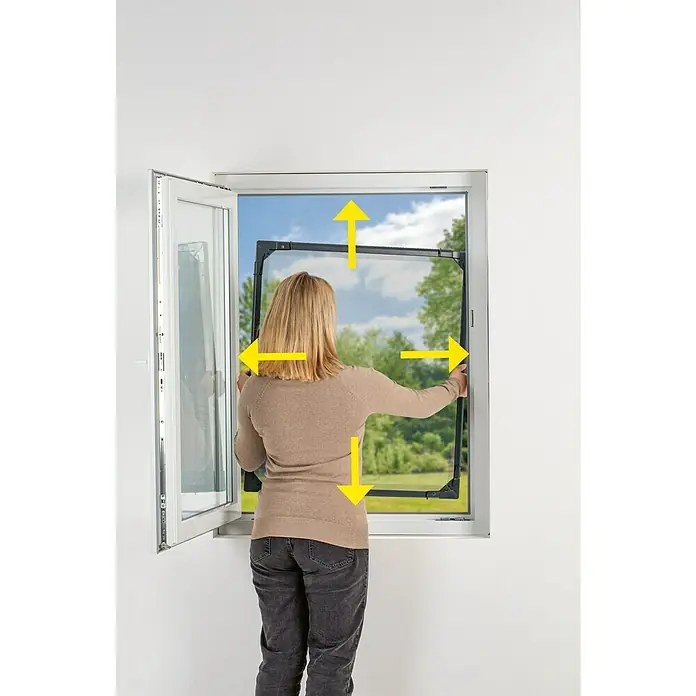 Easy Maxx Insektenschutzfenster - B x H: 115 x 135 cm, Montage Insektengitter: Klemmen, Farbe Rahmen: Weiß - Frau montiert einen schwarzen Insektenschutzrahmen in ein Fenster. Ideal, um Insekten fernzuhalten und frische Luft hereinzulassen.