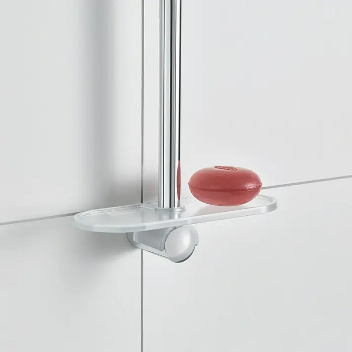Grohe Easy Reach Seifenschale - Geeignet für: Brausestangen mit 22 mm Rohrdurchmesser - Nahaufnahme einer transparenten Seifenablage mit einer roten Seife darauf, befestigt an einer Duschstange und weißen Fliesen.