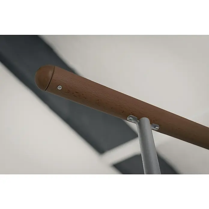 Minka Spindeltreppe Venezia - Durchmesser: 120 cm, Grau, Farbe Stufen: Buche Walnuss gebeizt, Geschosshöhe: 305,5 cm - Eine Nahaufnahme einer Holzhandlaufbefestigung an einer Wand, die mit Schrauben an einem grauen Metallpfosten befestigt ist.