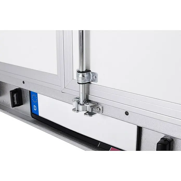 Stema Kofferanhänger P-Box 2000 - Nutzlast: 1.298 kg, Doppelachser, Kasteninnenmaß: 305 × 157 x 184 cm - Nahaufnahme einer weißen Anhänger-Laderaumtür mit silbernem Alurahmen, metallischem Verschlussmechanismus und Kennzeichenausschnitt.