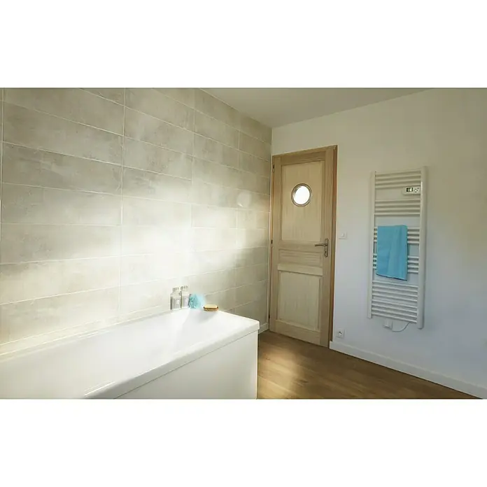 Mottez Bullauge - Metall, Silber, Optik Glas: Klarglas, Durchmesser: 26 cm - Ein Badezimmer mit einer weißen Badewanne und einem weißen Handtuchwärmer an der Wand. Der Raum ist hell und freundlich gestaltet.