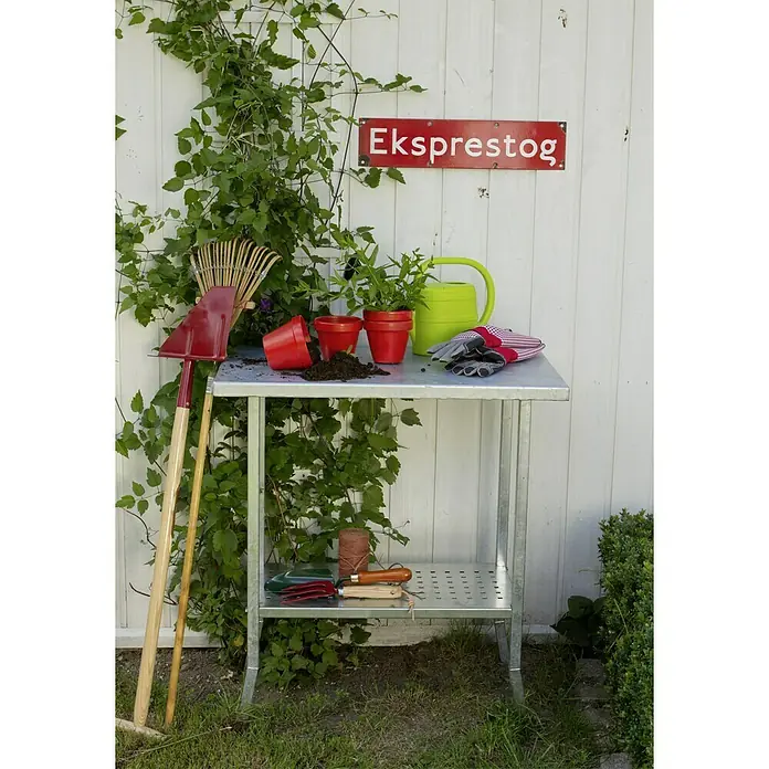 Plus Gartentisch / Pflanztisch - 75 x 45 x 80 cm - Gartentisch mit Gartengeräten und Pflanzen, die auf der Tischplatte stehen. Über dem Tisch hängt ein Schild mit der Aufschrift "Eksprestog".