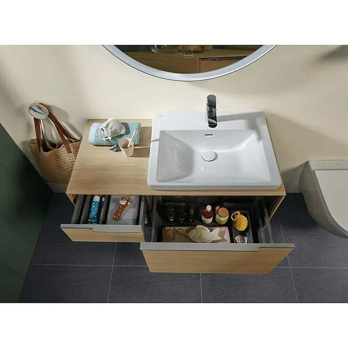 Villeroy & Boch Subway 3.0 Waschbeckenunterschrank - Nordik Oak, Anzahl Schubladen: 2 Stk., Farbe Griff: Aluminium glänzend, B x T x H: 100,1 x 51,6 x 42,3 cm, Offenes Fach links - Badezimmermöbel aus hellem Holz mit weißem Keramikwaschbecken und Chromarmatur, Schubladen mit Badprodukten geöffnet.