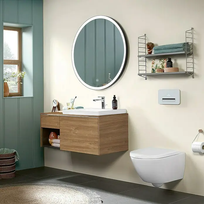 Villeroy & Boch Subway 3.0 Waschbeckenunterschrank - Kansas Oak, Anzahl Schubladen: 2 Stk., Farbe Griff: Aluminium glänzend, B x T x H: 100,1 x 51,6 x 42,3 cm, Offenes Fach links - Modernes Badezimmer mit schwebendem Holzwaschtisch, weißem Waschbecken, rundem beleuchteten Spiegel und wandhängender Toilette. Petrol- und hellbeige Wände.