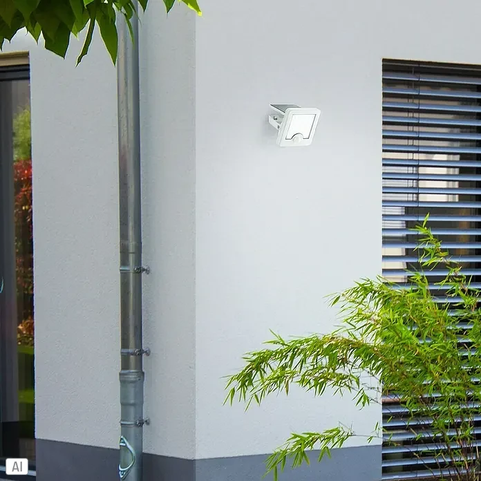 Brilliant Solar-Außenwandleuchte Luton - 4 W, L x B x H: 13 x 12 x 5,4 cm, Weiß, IP65, 540 lm - Weißer Outdoor-LED-Strahler an Hauswand, bietet Sicherheitsbeleuchtung neben einem Fenster.