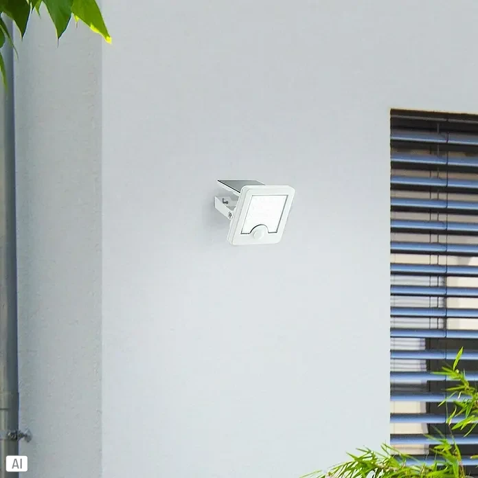 Brilliant Solar-Außenwandleuchte Luton - 4 W, L x B x H: 13 x 12 x 5,4 cm, Weiß, IP65, 540 lm - Weißes Solar-Außenlicht mit Bewegungssensor an einer Wand montiert.