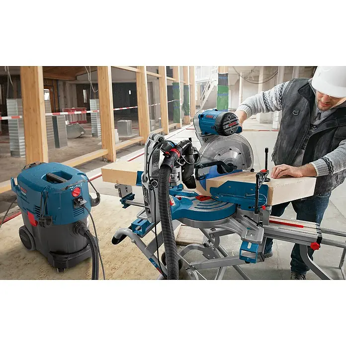 Bosch Professional Kapp- & Gehrungssäge GCM 12 GDL - 2.000 W, Durchmesser Sägeblatt: 305 mm, Leerlaufdrehzahl: 4.000 U/min - Nahaufnahme einer Bosch Kapp- und Gehrungssäge mit einem Arbeiter, der ein Holzstück bearbeitet, begleitet von einem Bosch Staubsauger.