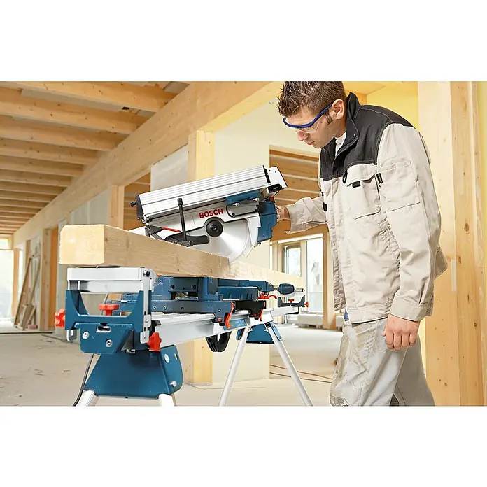 Bosch Professional Tischkreissäge GTM 12 JL - 1.800 W, Durchmesser Sägeblatt: 305 mm - Ein Handwerker in Arbeitskleidung bedient eine Bosch Kapp- und Gehrungssäge beim Holzzuschnitt auf einer Baustelle.