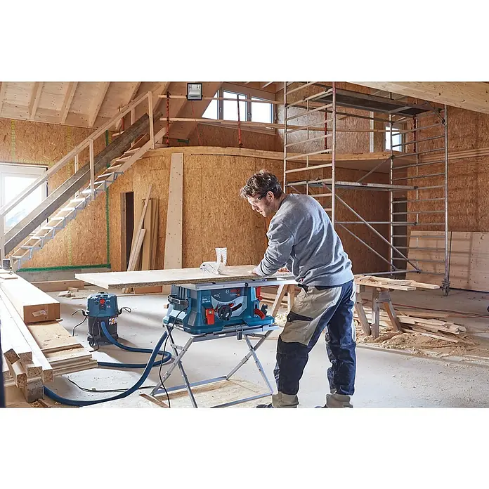 Bosch Professional Untergestell GTA 560 - Arbeitshöhe: 564 mm, Passend für: Bosch Tischkreissäge GTS 635-216 - Ein Handwerker arbeitet mit einer Bosch GTS 635-216 Tischkreissäge in einer Baustelle.